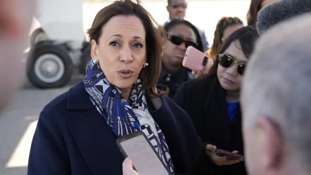 Harris speaks to reporters on the tarmac by a plane