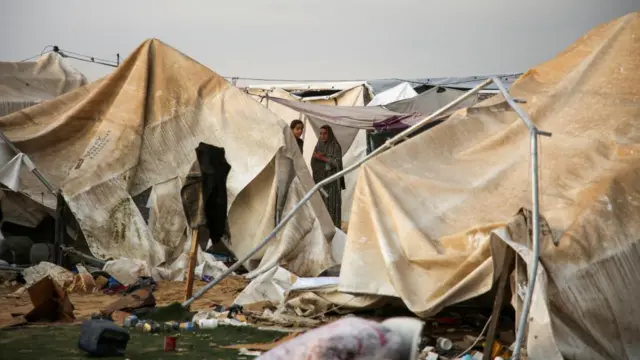 Palestinians inspect the damage at the site of an Israeli strike on a tent camp sheltering displaced people in Khan Younis on Tuesday