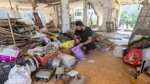 A man looks through his belongings in his badly damaged home in central Gaza