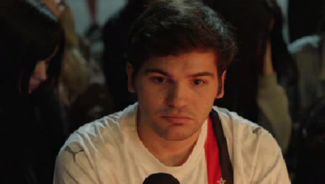 An Argentinian One Direction fan in the centre of the picture wearing white football shirt with red and black stripes on left shoulder, attending a vigil for Liam Payne