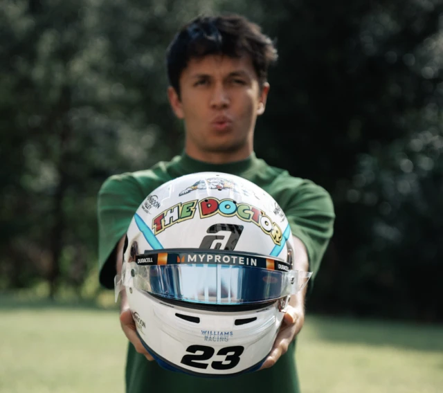 Alex Albon holds his special helmet for his 100th grand prix