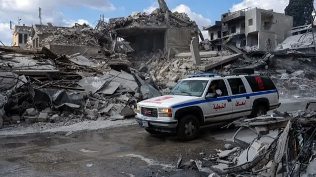 An ambulance drives past the remains of buildings in Nabatieh.