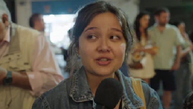 A female One Direction fan in denim jacket with yellow bag hoisted up on left shoulder speaks at a vigil in Buenos Aires