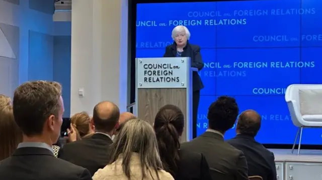 Treasury Secretary Janet Yellen stands at a podium and addresses a crowd