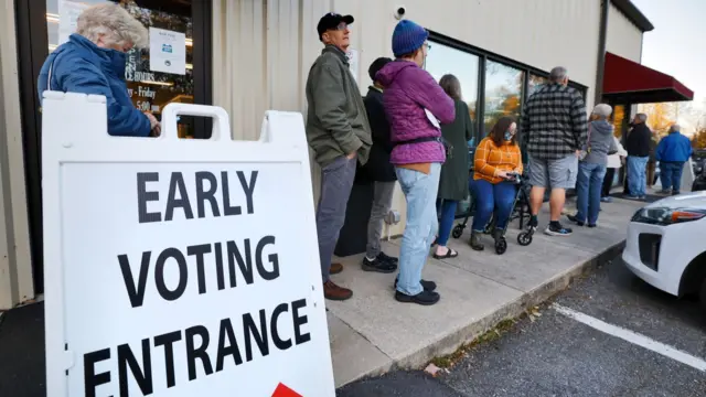 A queue of people line up to vote behind an early voting sign in Marion, North Carolina