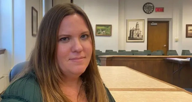 A woman in a green dress in a municipal office looking at the camera