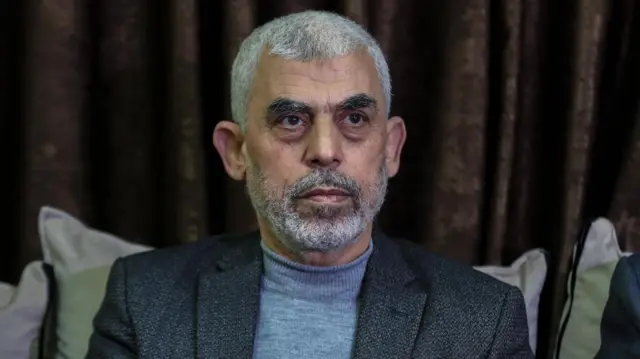 Yahya Sinwar sitting in front of a curtain