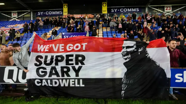 Exeter fans hold up a Gary Caldwell banner