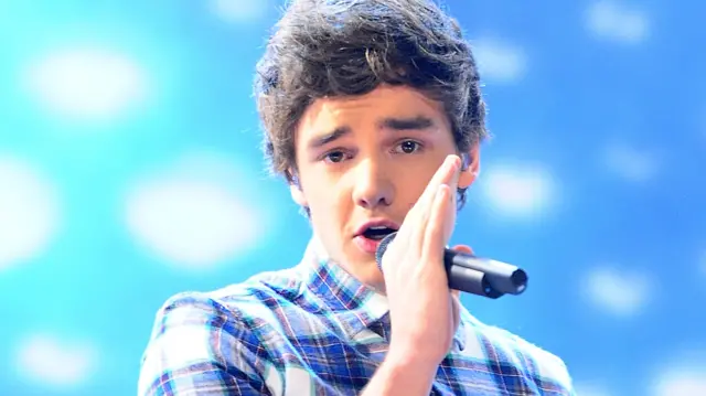 Liam Payne performs on stage with a chequered shirt and with a mic in his hand