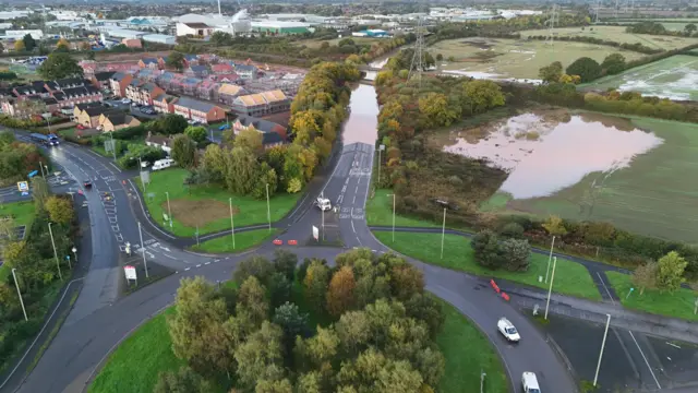 Drone shot showing water deluging Battlefield Link Road north of Shrewsbury. A neighbouring field is also under water.