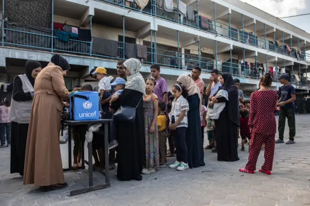 People queue with their children for polio vaccinations at a make-shift camp for those displaced by conflict in a school run by Unrwa in Khan Yunis in the southern Gaza Strip