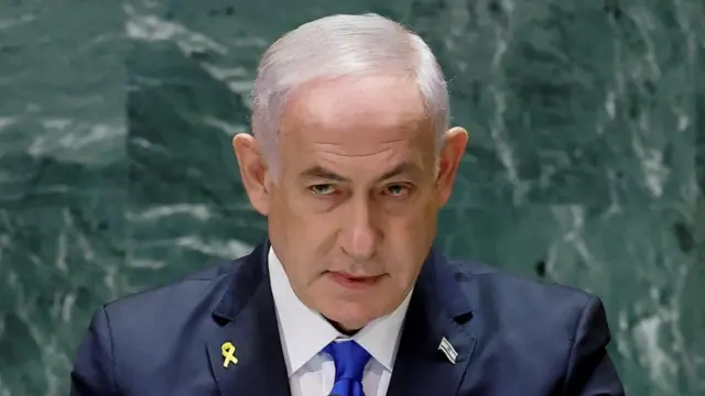 Close up shot of Israeli Prime Minister Benjamin Netanyahu, he is stood in front of a green background