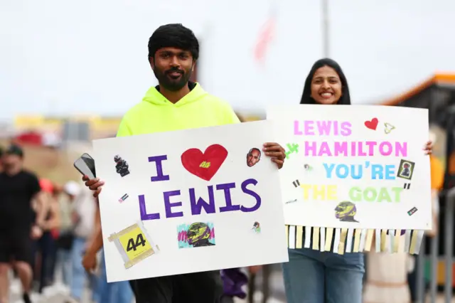 Fans hold up Lewis Hamilton signs