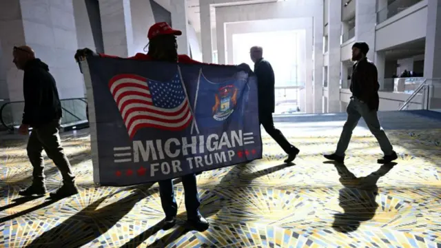 A man carries a flag that says "Michigan for Trump"