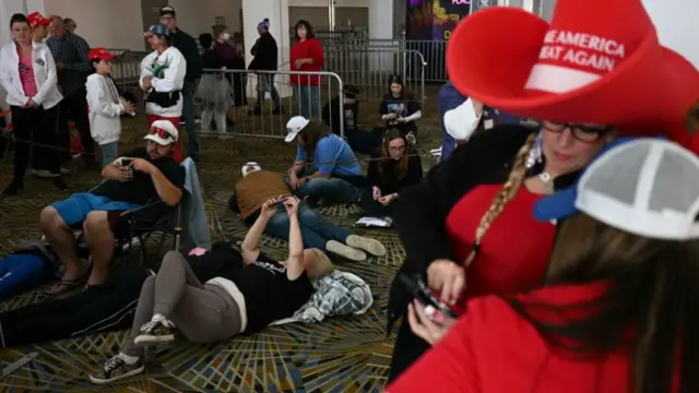 Trump fans, some lying on the floor on their phones, queue early for his rally in Detroit