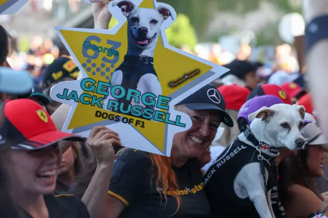 A fan holds a dog and a George Russell sign