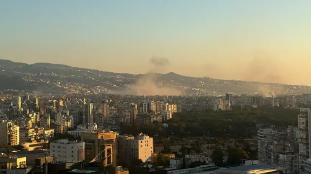 View of Beirut as smoke rises above buildings with the sunset in the background