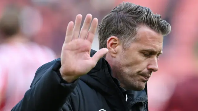 Rob Edwards waves a hand of apology to Luton fans