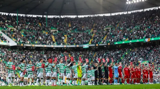 GLASGOW, SCOTLAND - OCTOBER 19: Both sets of players hold 'Show Racism the Red Card' cards during a William Hill Premiership match between Celtic and Aberdeen at Celtic Park, on October 19, 2024, in Glasgow, Scotland. (Photo by Ross MacDonald / SNS Group)