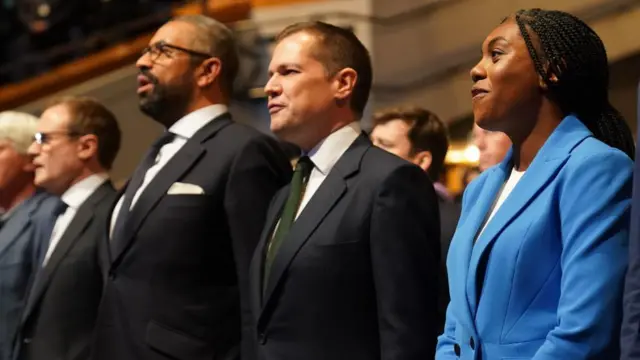 Tory leadership candidates, Tom Tugendhat, James Cleverly, Robert Jenrick and Kemi Badenoch, sing the national anthem after delivering their speeches at the Conservative Party Conference at the International Convention Centre in Birmingham