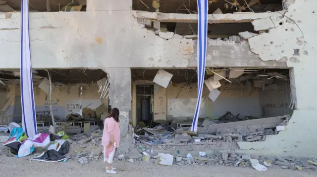 A woman stands amid the rubble of a building struck by Iran's rocket barrage on Israel