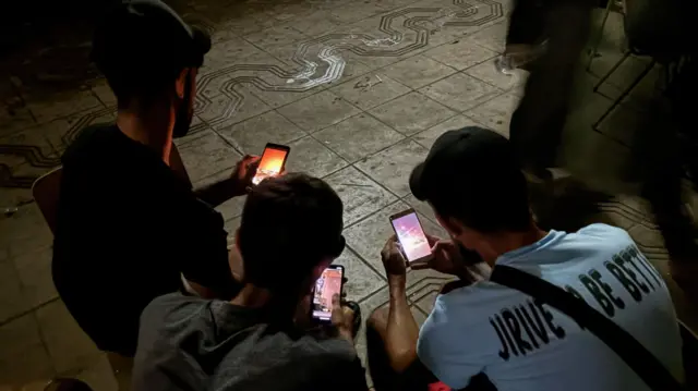 Three people look at their cell phones