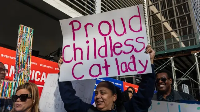 Women holds "proud childless cat lady" poster