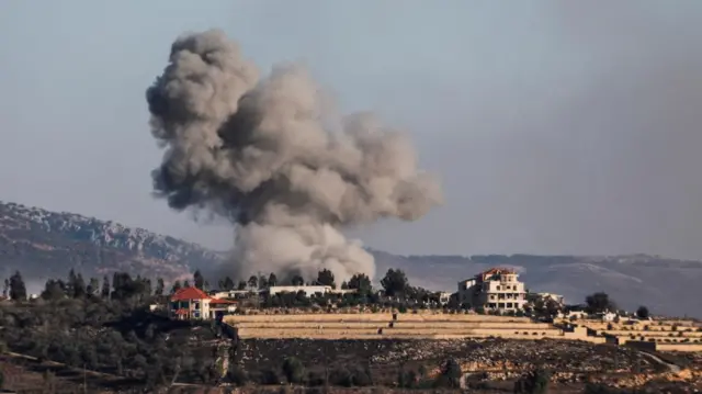 Smoke rises above Khiam in southern Lebanon with mountains beyond