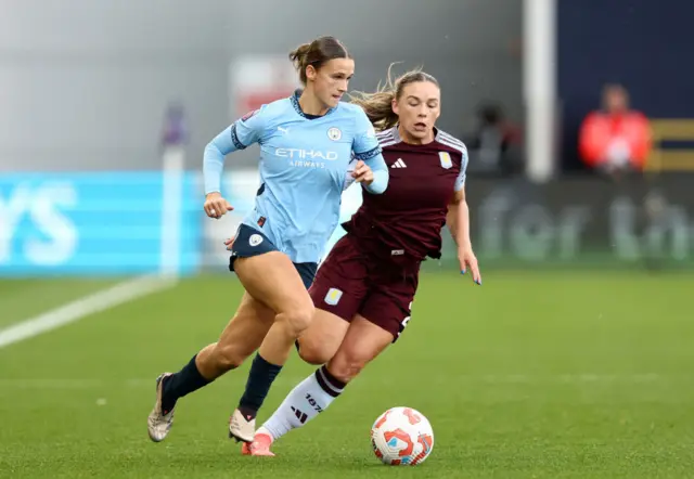 Kerstin Casparij of Manchester City runs with the ball under pressure from Kirsty Hanson