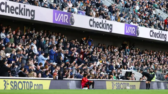 Referee Darren England checks the VAR screen during Fulham against Aston Villa