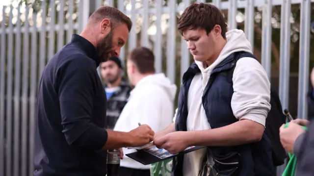 Bolton manager Ian Evatt signs autographs outside St Andrew's