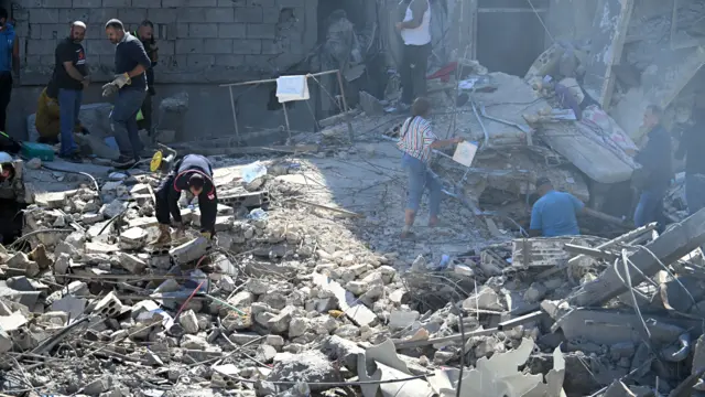 People and emergency services work at site of Israeli strike near the hospital