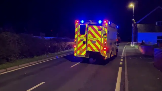 An ambulance is seen on a dark road