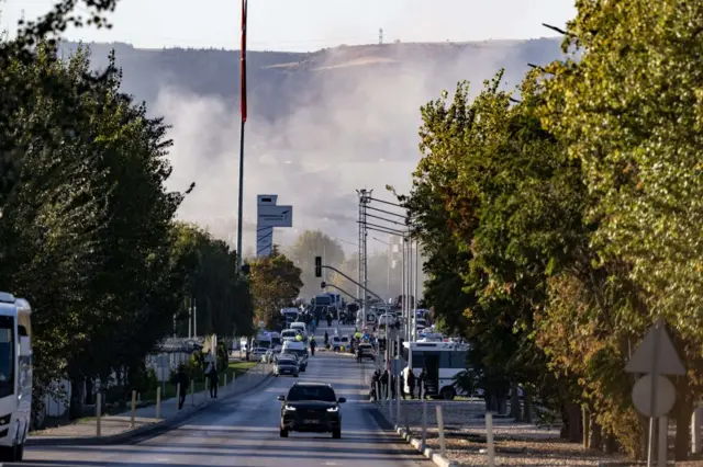 Smoke rises near TAI HQ, emergency services can be seen in the background