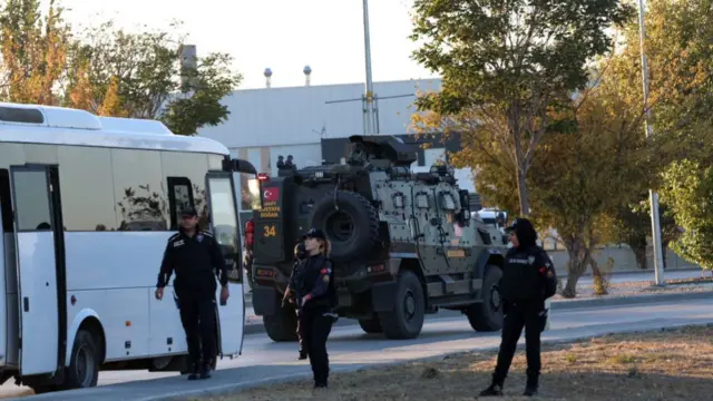 Police stand in front of an armoured vehicle at the scene