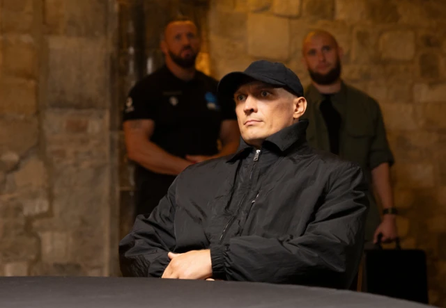 Oleksandr Usyk in a black cap and coat