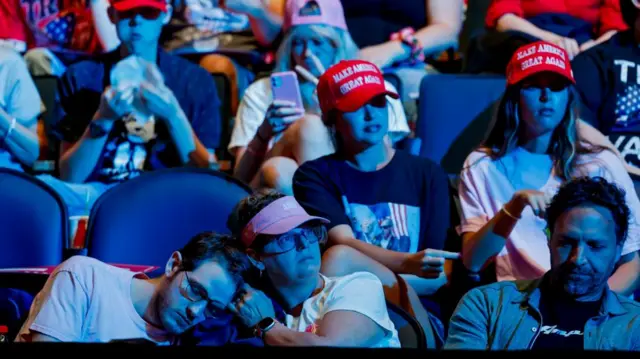 Supporters wearing Make American Great Again hats sit in the seats of an arena in Georgia.