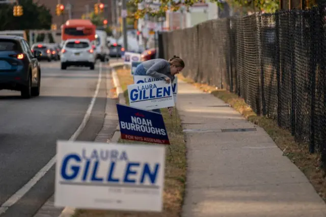 A volunteer installs campaign signs outside a Get Out the Vote rally for Lauren Gillen, Democratic Congressional candidate in New York, not pictured, at Kennedy Memorial Park in Hempstead, New York, US