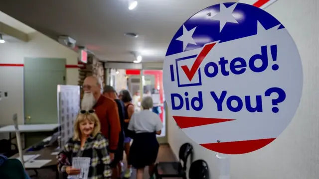 Voters cast their ballots during early voting for the US presidential election and other races at Buncombe County's Black Mountain Library in Black Mountain, North Carolina. A large sign reading "I voted! did you?" can be seen in the foreground.