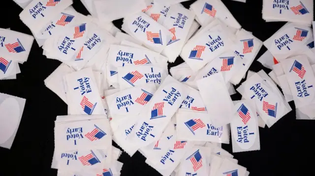 Early voting stickers are seen spilled out across a table with the words 'I voted early' written on them.