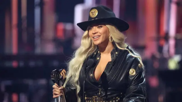 Beyoncé stands a a podium with an award