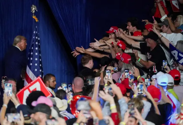 Supporters gesture towards Republican presidential nominee and former U.S. President Donald Trump during a rally at Mullett Arena in Tempe, Arizona