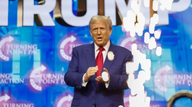 Donald Trump claps at the front of the stage during a rally