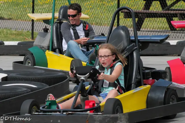 Cimarron is in a gokart, her father Ben is in the gokart behind her