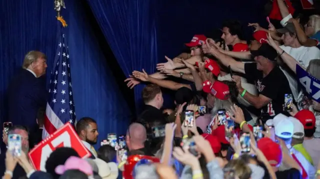 Supporters gesture towards Republican presidential nominee and former U.S. President Donald Trump during a rally at Mullett Arena in Tempe, Arizona