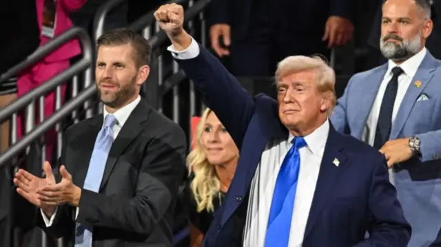 In the audience of the RNC, Eric Trump claps as his father raises a fist in the air