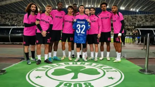 Chelsea players pose with a shirt paying tribute to George Baldock before they play Panathinaikos