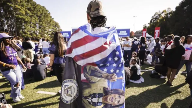 A man draped in a flag depicting US presidential candidate Kamala Harris