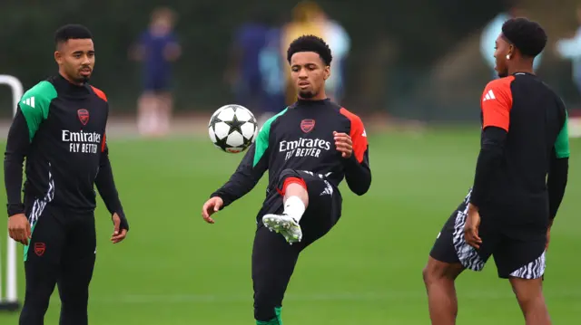 Ethan Nwaneri kicks a ball at Arsenal training as team-mate Gabriel Jesus watches on