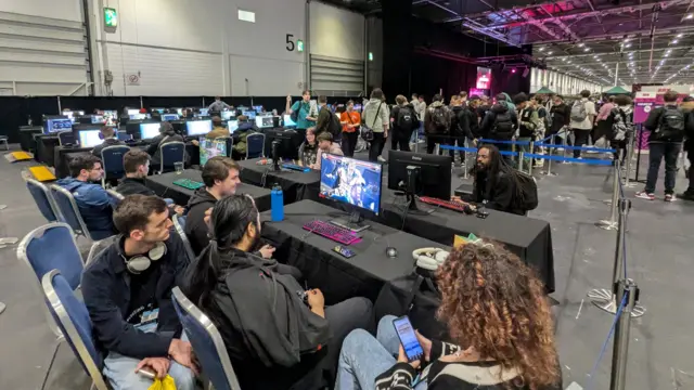 Gamers seated in front of screens playing video games at the EGX game show